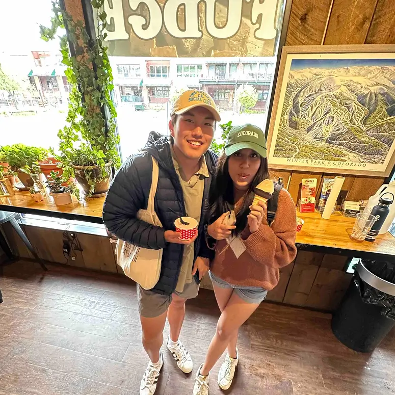 two young adults smiling while holding ice cream cones
