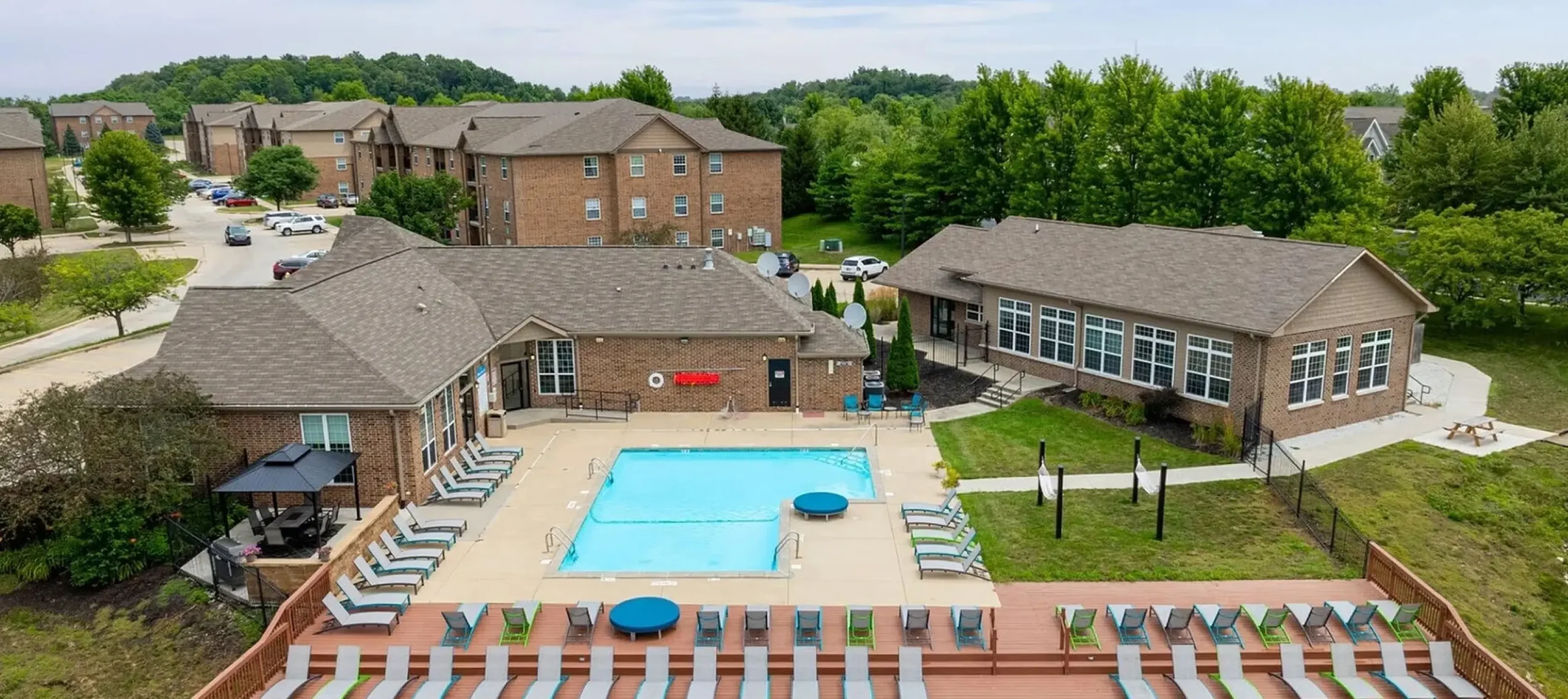 Arial shot of apartment community pool with lounge seating and ample parking
