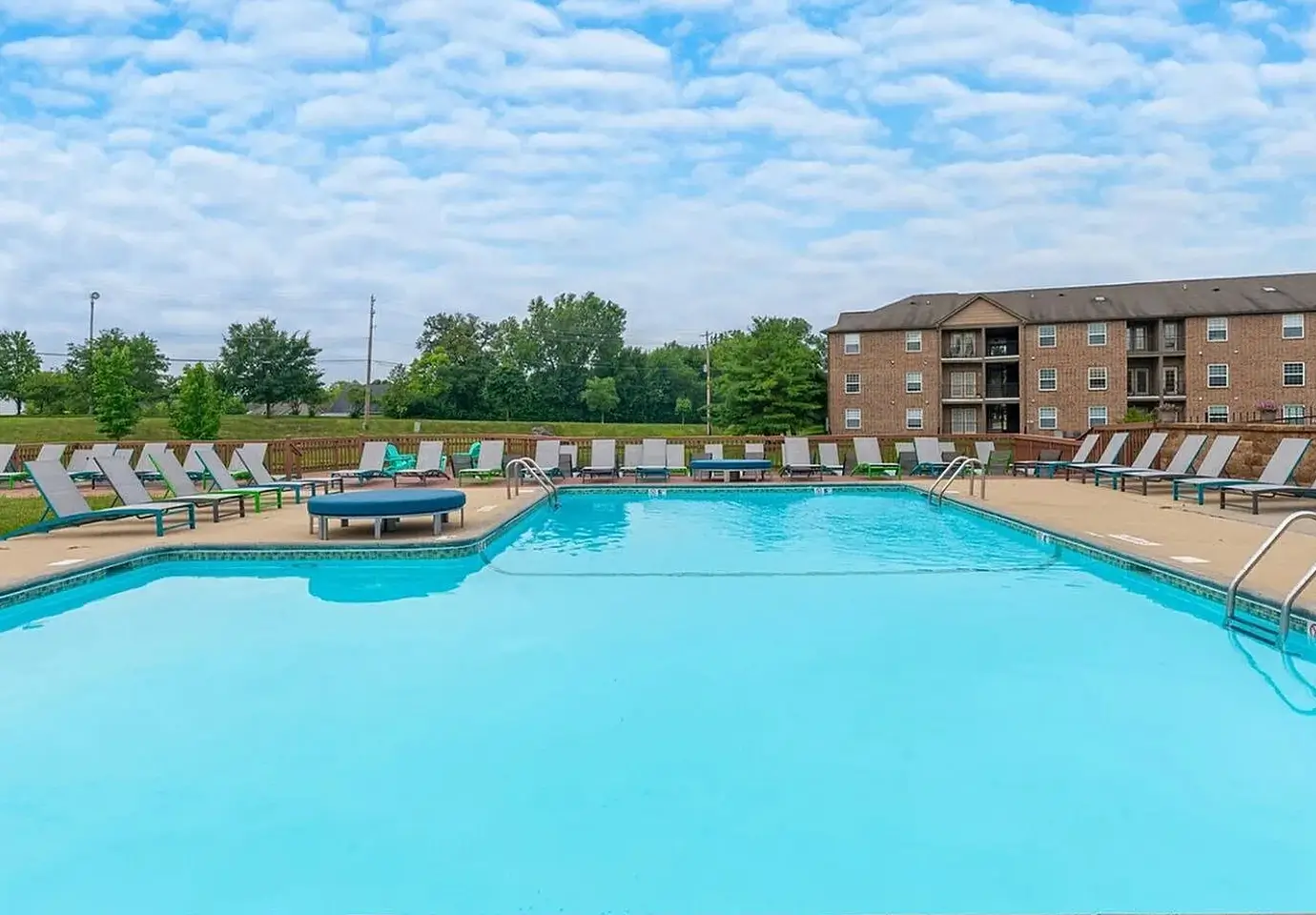 an apartment community pool surrounded by lounge chairs